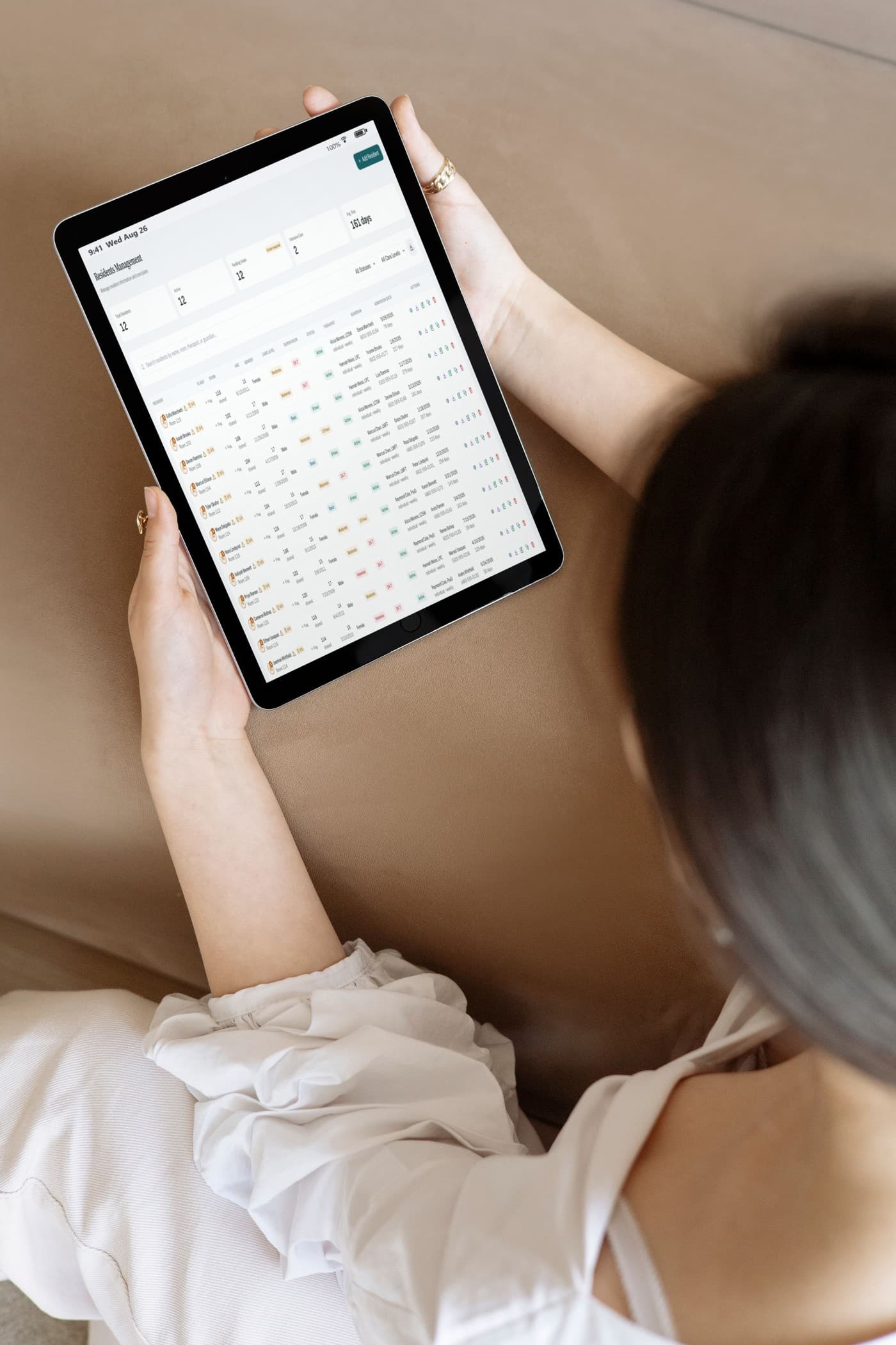 A staff member on a couch reviewing a resident chart in Dacnus on a tablet